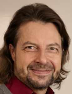 Maik Marx von plangenial.de im Team-Portrait – selbstbewusst und professionell in die Kamera blickend.